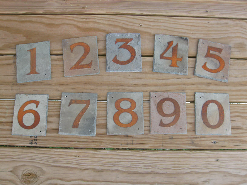 Square pieces of slate with golden numbers 1 through 0 stenciled on